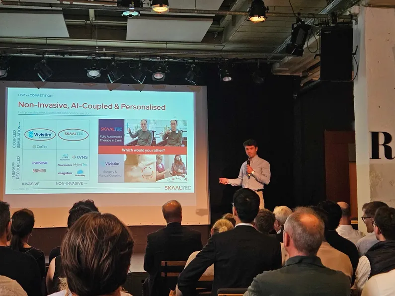 Skaaltec presenting on stage to an audience of investors, with a slide reading 'Non-Invasive, AI-Coupled & Personalised'.