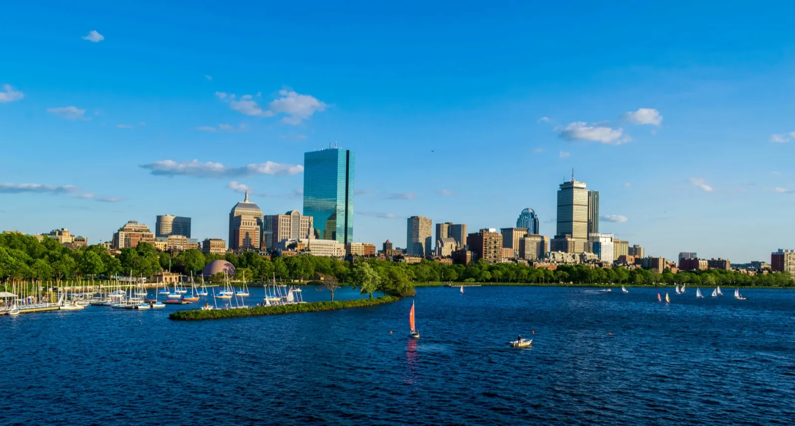 Boston skyline along the Charles River with sailboats on the water under a blue sky, marking Skaaltec's upcoming Venture Leaders Medtech roadshow to Boston.